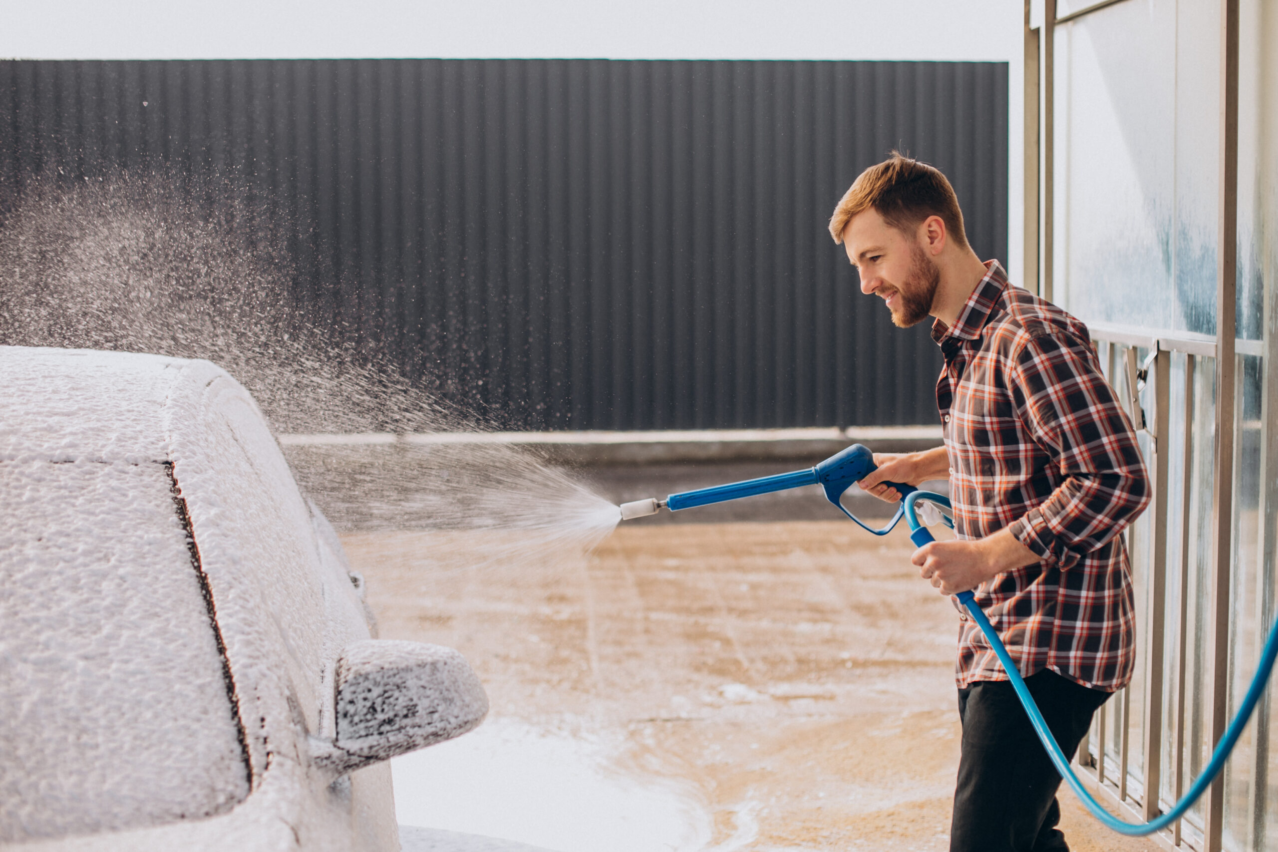 Young man washing his car at carwash